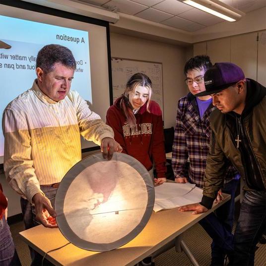 GIS professor teaching students using light and maps.